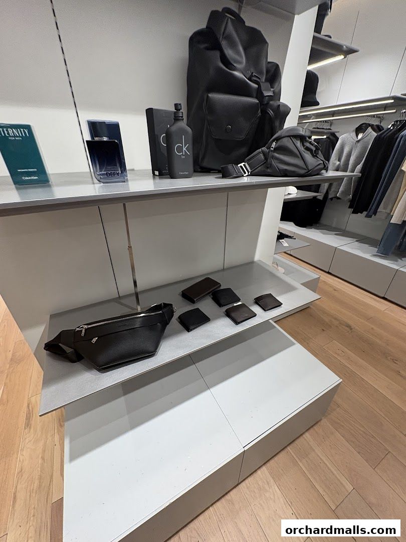 Calvin Klein store interior showcasing fragrances, bags, wallets, and apparel on display shelves.