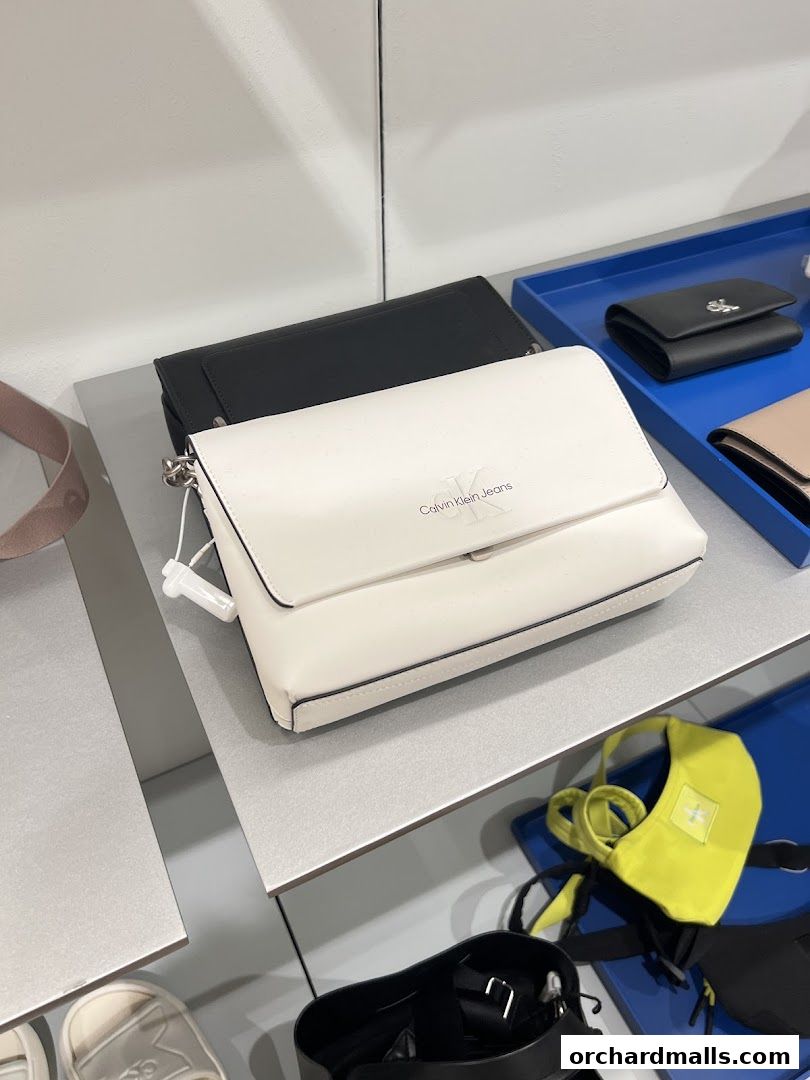 A display of Calvin Klein handbags and accessories on shelves in a retail store.