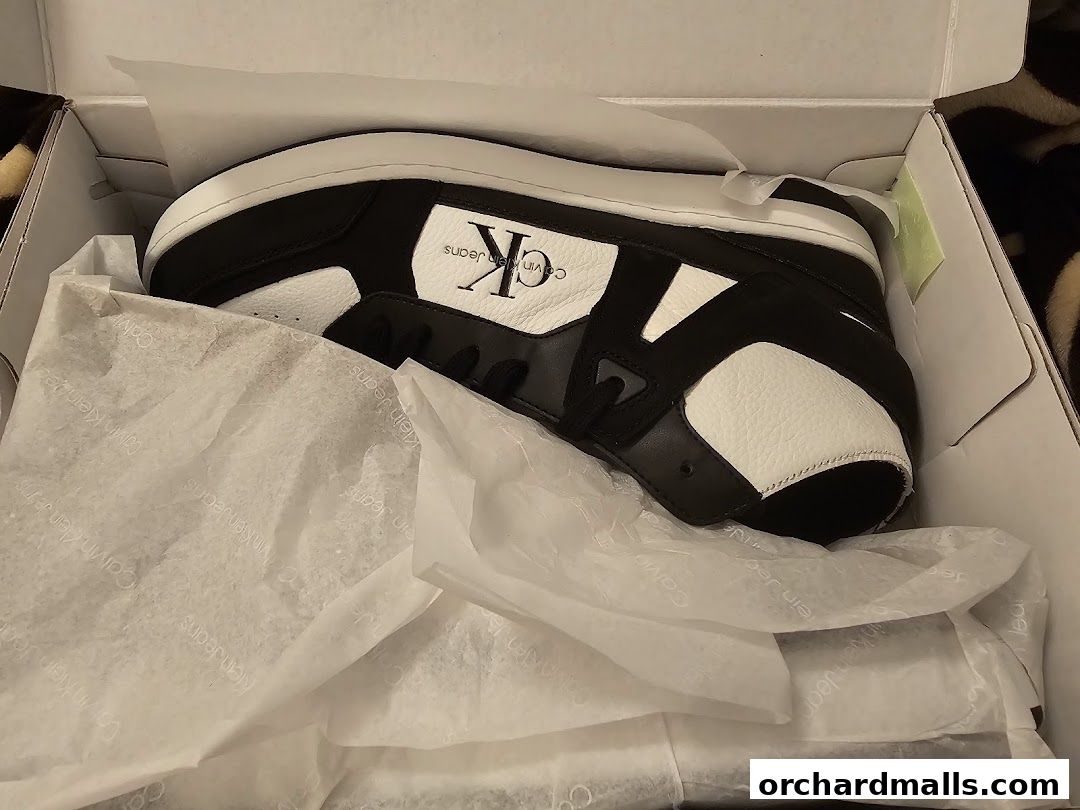A pair of black and white Calvin Klein sneakers in their original packaging.
