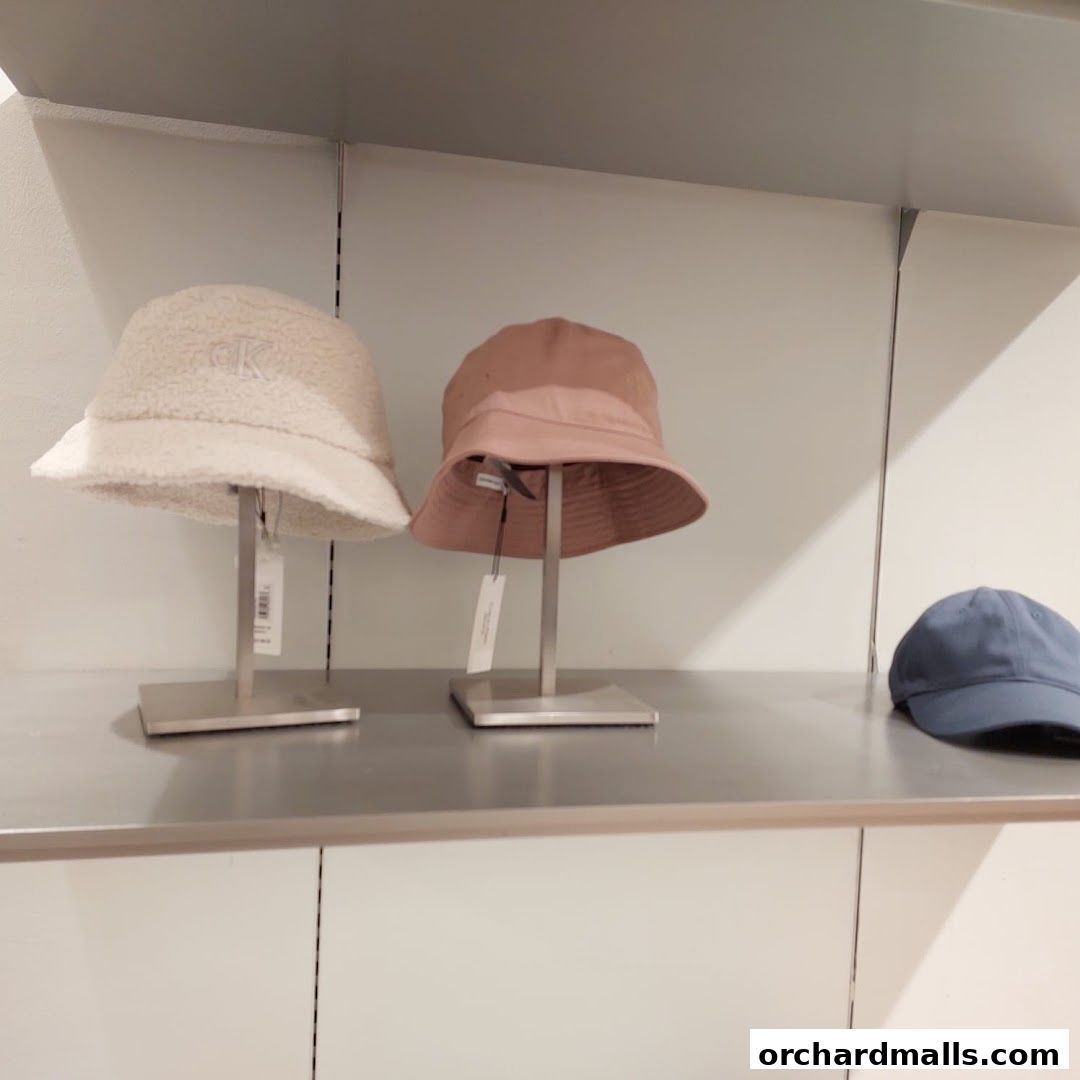 Three bucket hats displayed on stands in a retail store, with one blue baseball cap visible.
