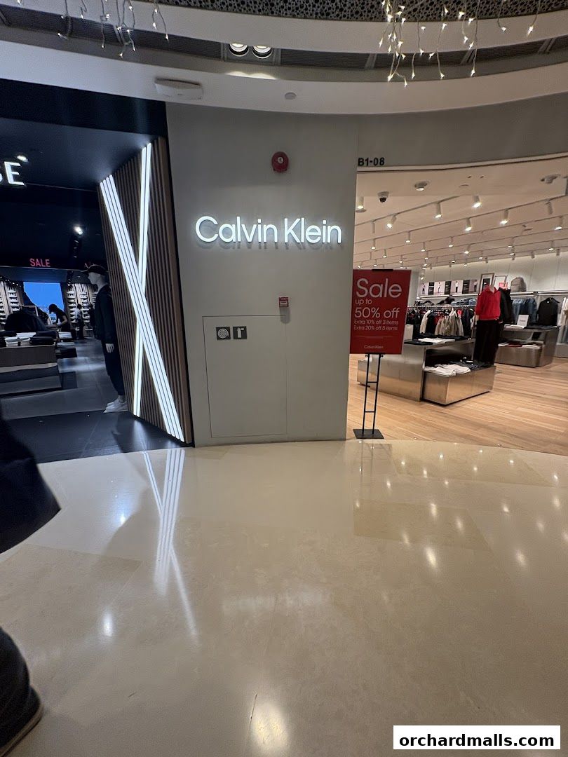 The entrance to a Calvin Klein store with a sale sign displayed.