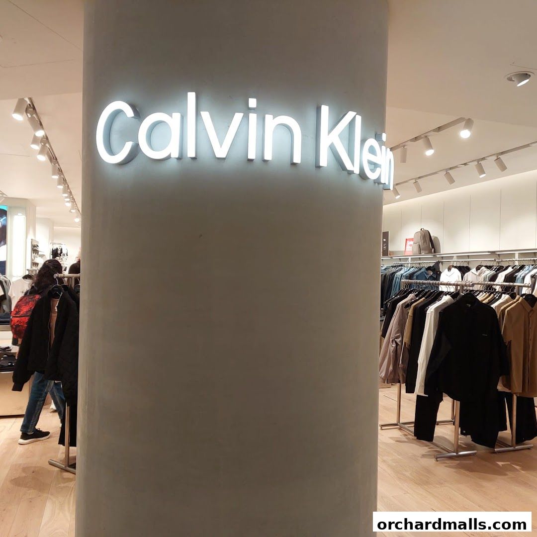 Interior view of a Calvin Klein store with clothing racks and illuminated signage.