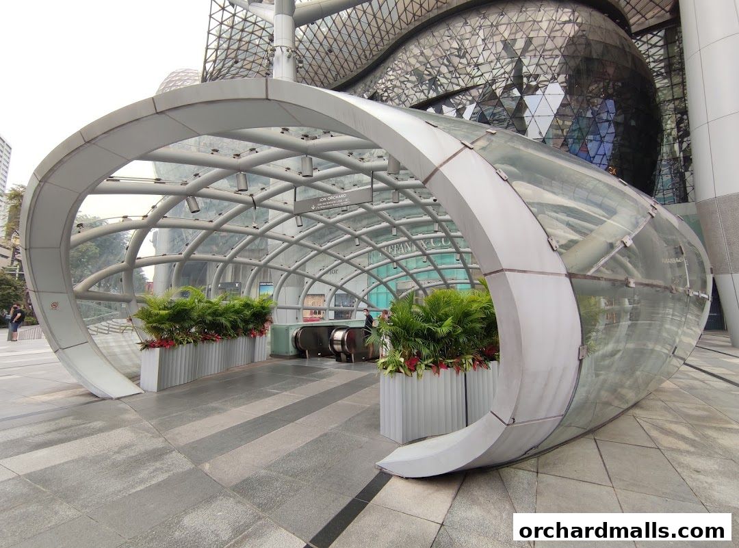 Modern glass and metal walkway leading to escalators at ION Orchard.