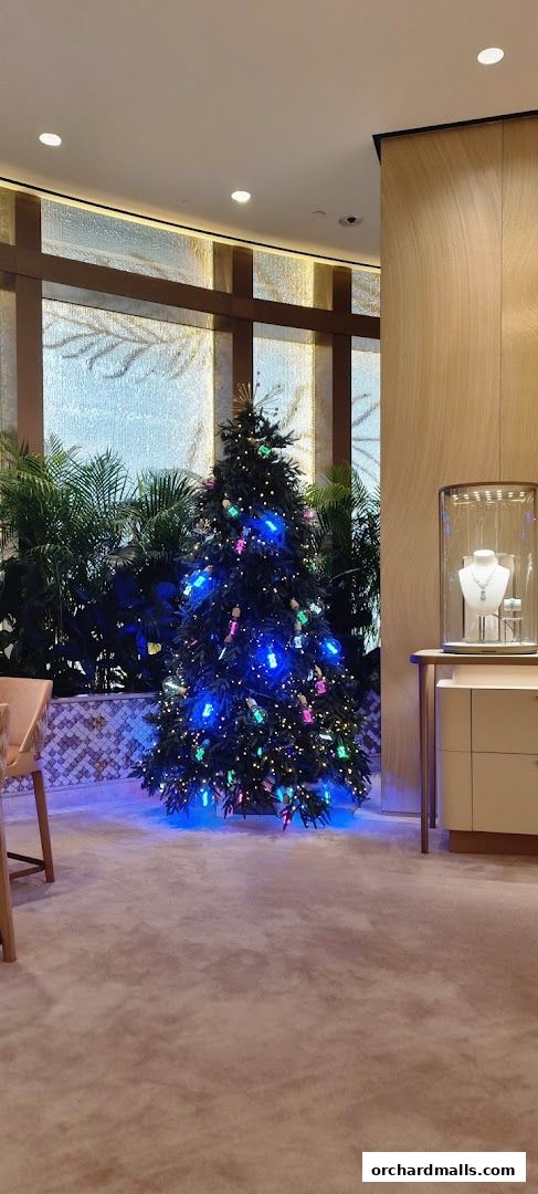 A beautifully decorated Christmas tree with colorful lights inside a luxurious jewelry store.