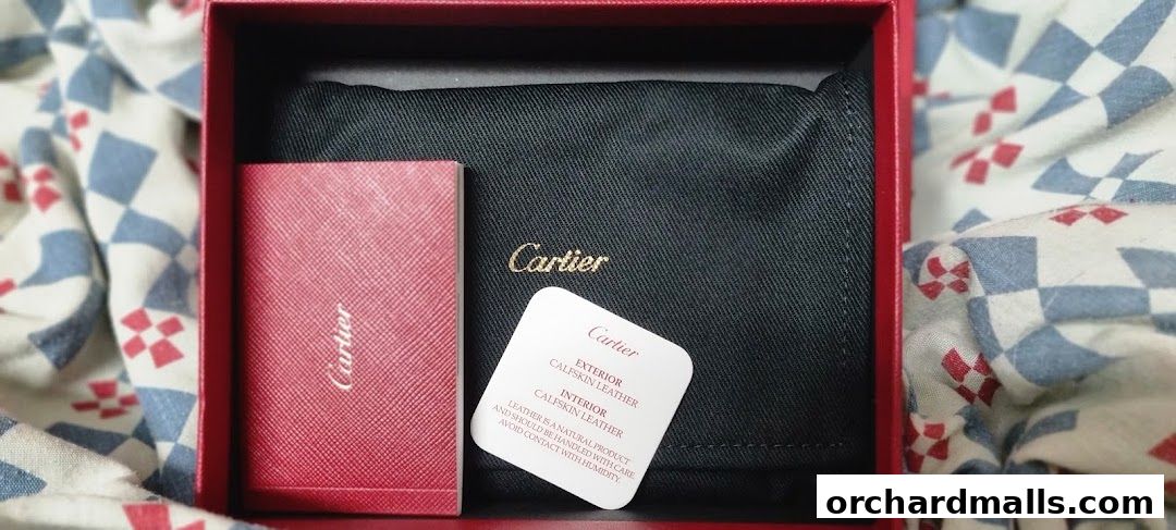 A red Cartier box containing a black pouch and product information card.