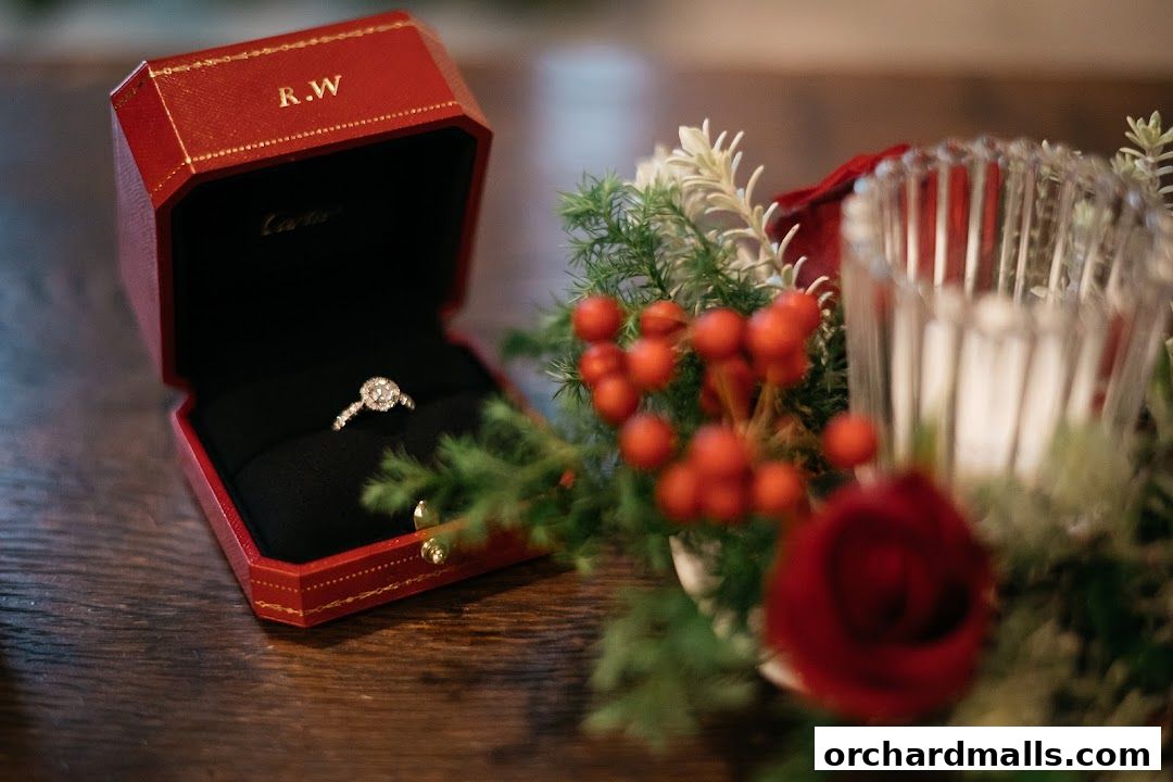 A Cartier ring in its iconic red box, next to festive greenery and berries.