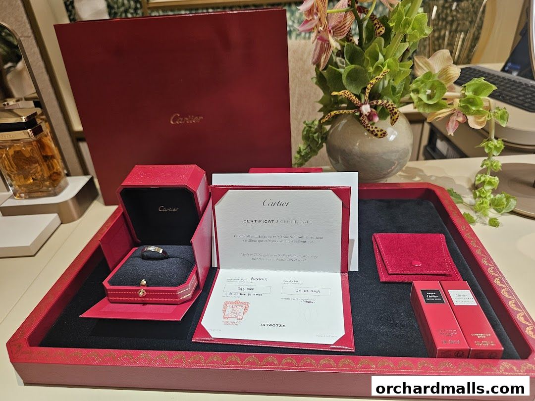 Cartier ring, certificate, perfume, and gift boxes displayed on a red tray.