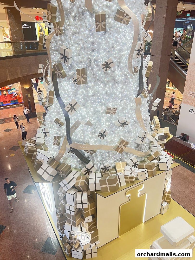 A festive display with a white Christmas tree adorned with gift boxes and Chanel ribbons.