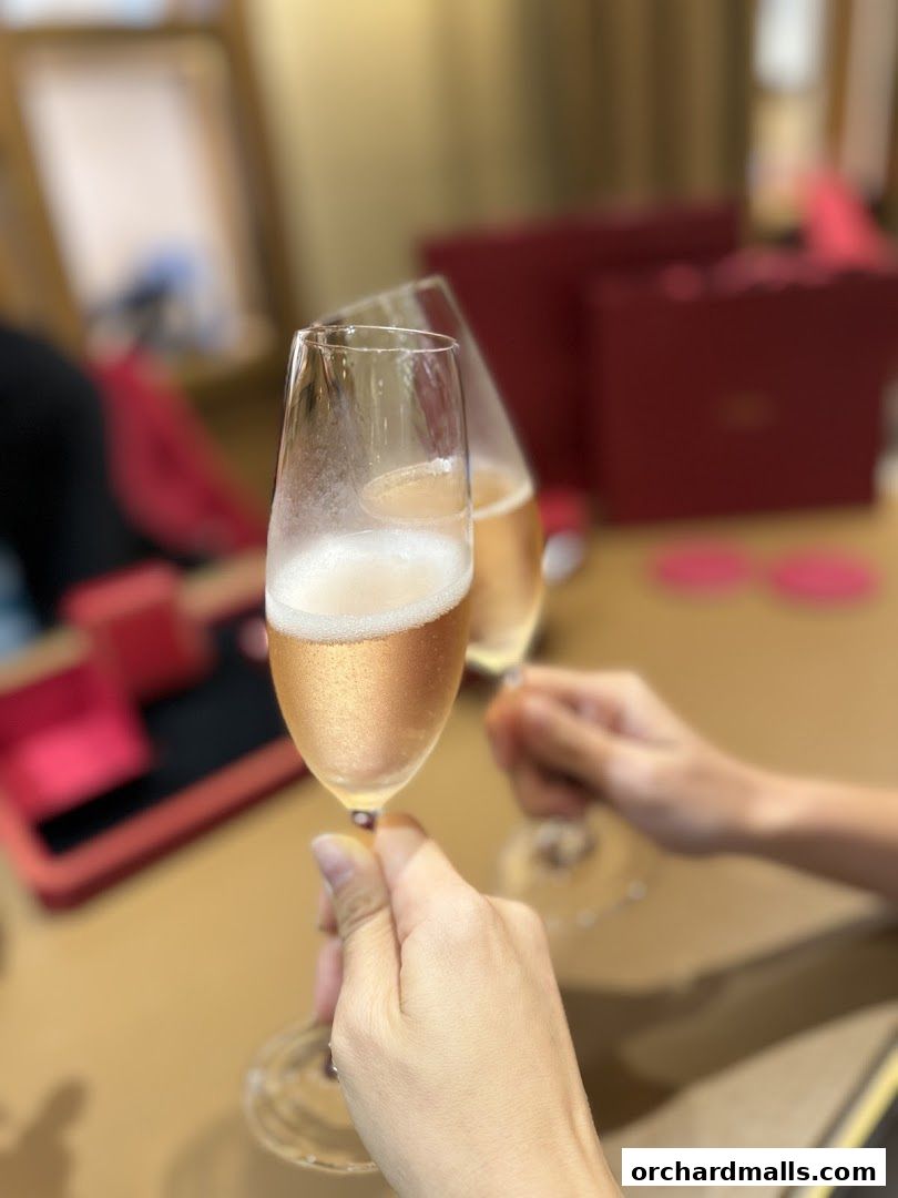 Two glasses of champagne are being toasted in front of Cartier gift boxes.