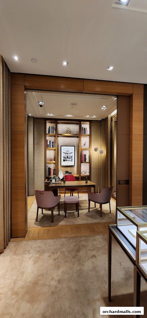 Interior view of a luxurious Cartier boutique with a desk, chairs, and bookshelves.