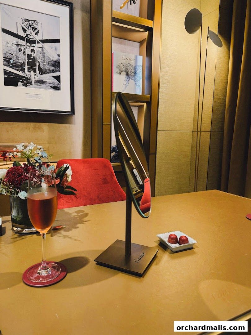 A table setting at Cartier with a glass of rose, flowers, and chocolates.