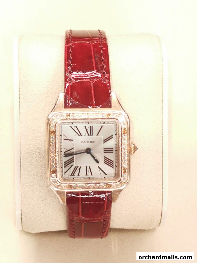A close-up of a luxurious Cartier watch with a red alligator strap and diamond bezel.