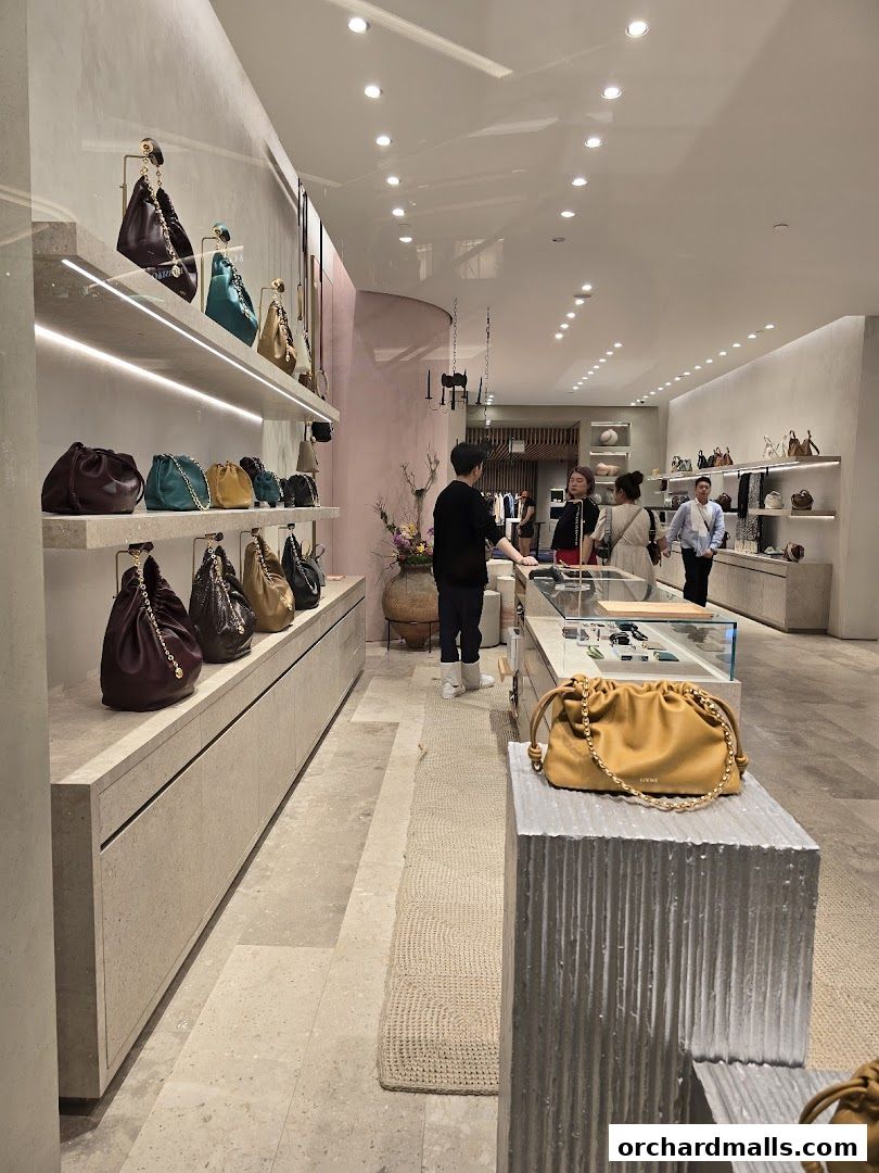 Interior of a luxury fashion store showcasing handbags on display shelves and a yellow handbag on a pedestal.