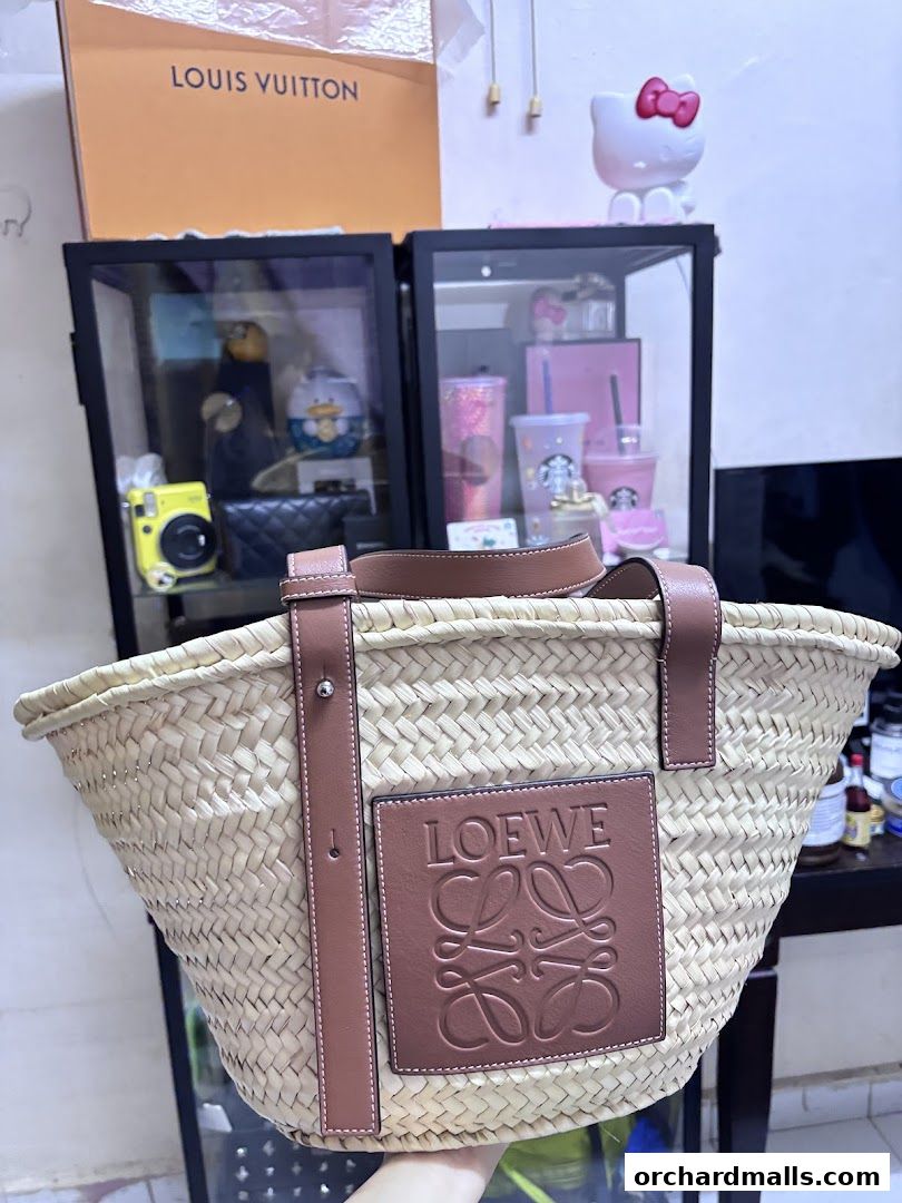 A person holds a straw basket bag with a prominent Loewe logo.