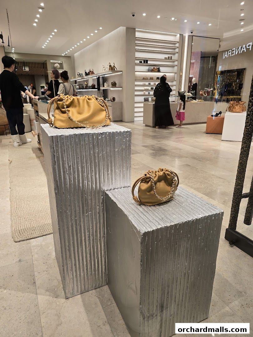 Interior of a luxury fashion store showcasing handbags on display pedestals.