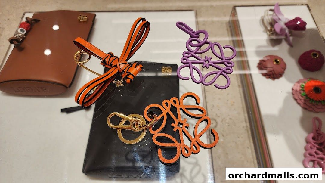 Close-up of Loewe leather accessories, including keychains and charms, displayed in a shop window.