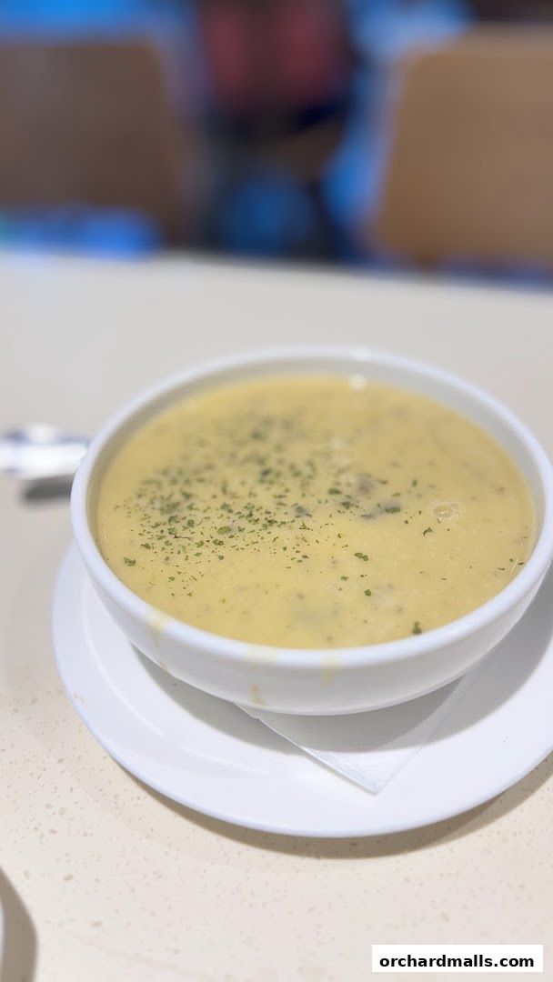 A close-up shot of a bowl of creamy soup topped with herbs.