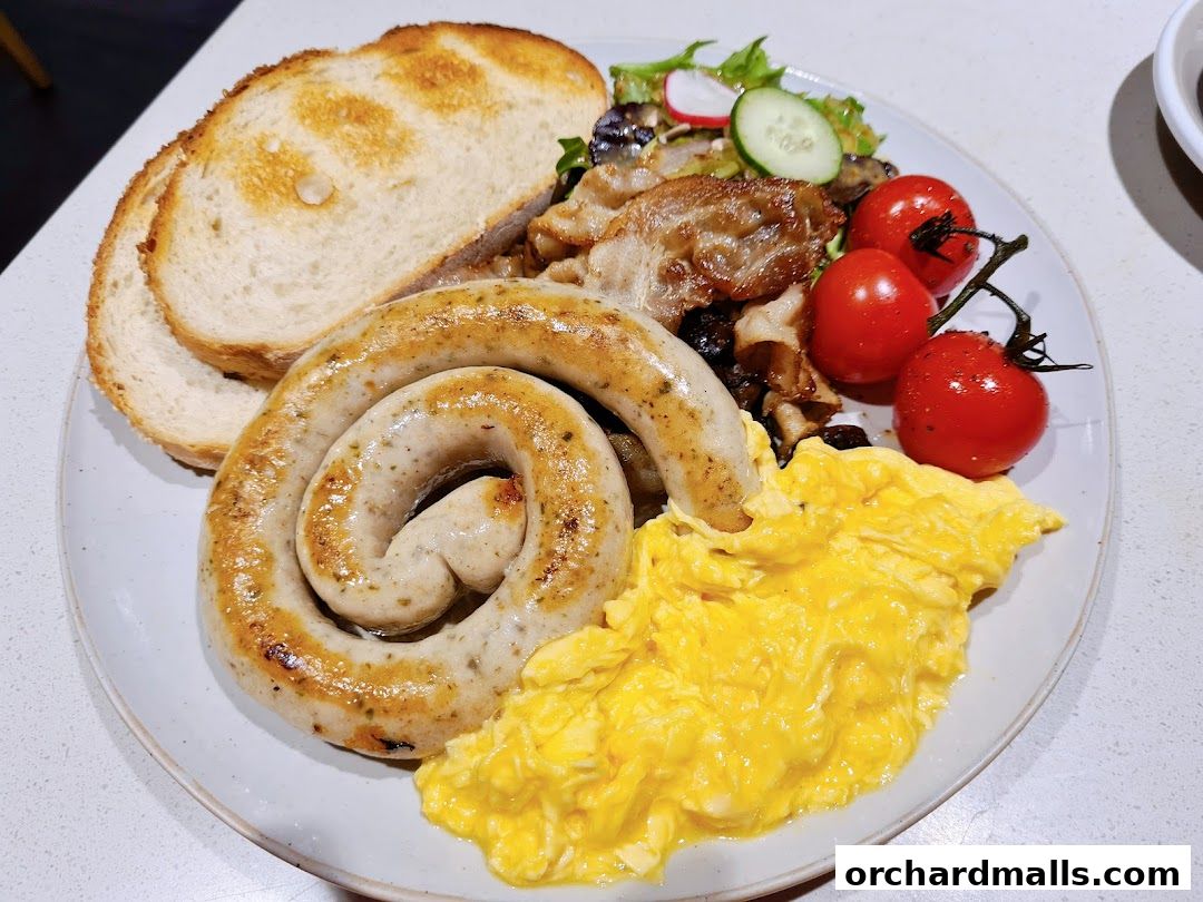 A hearty breakfast plate with a coiled sausage, scrambled eggs, toast, and cherry tomatoes.