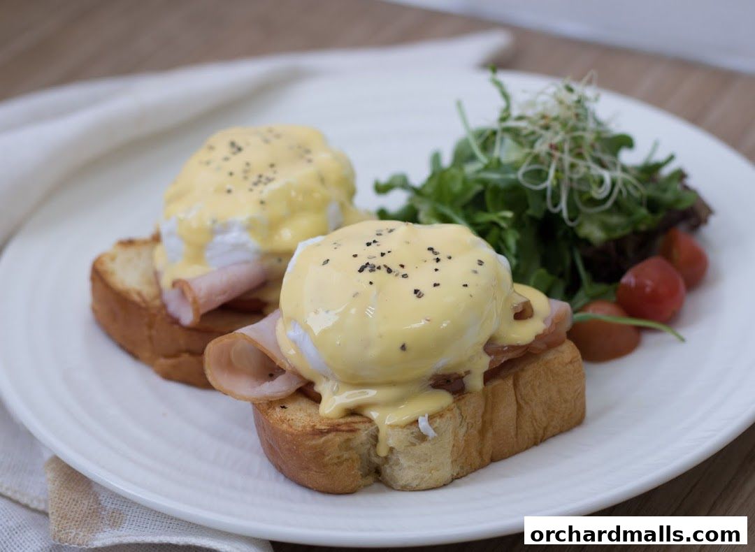 Two perfectly poached eggs with hollandaise sauce and ham on toast, served with a side salad.