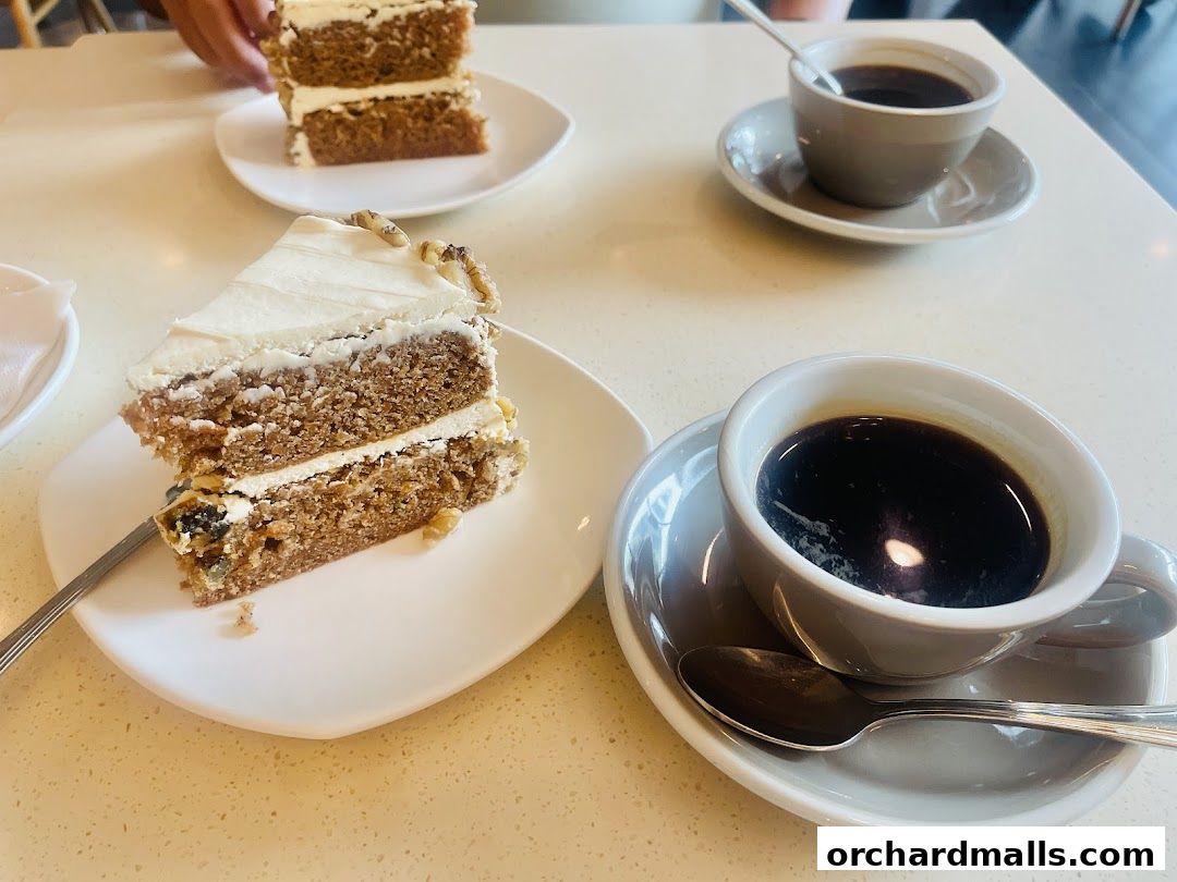 Two slices of layered cake with cream frosting and two cups of coffee on a table.