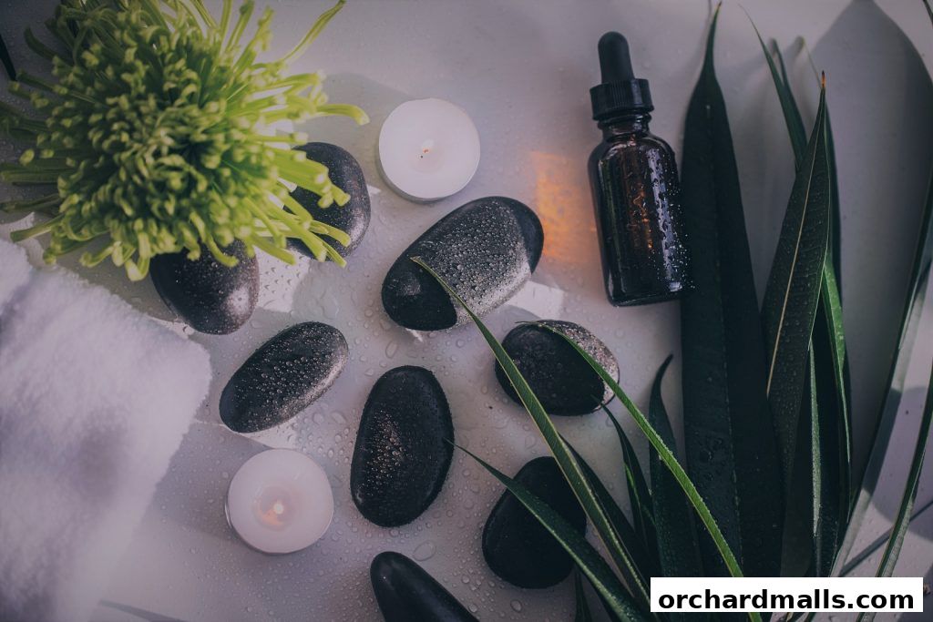 A serene arrangement of massage stones, candles, a flower, and oil for a spa experience.