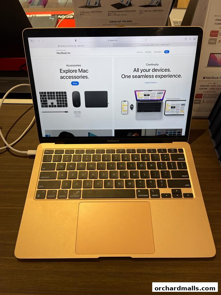 A gold MacBook Air open on a display, showing Apple's website with accessories and continuity features.