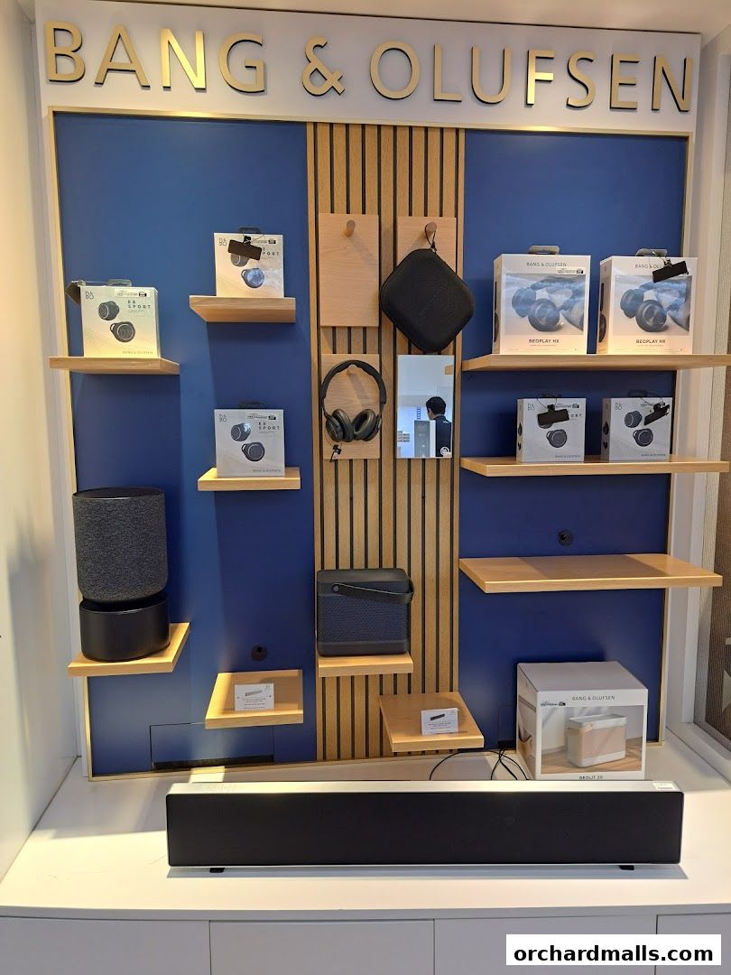 A display of Bang & Olufsen audio products including headphones, speakers, and soundbars.