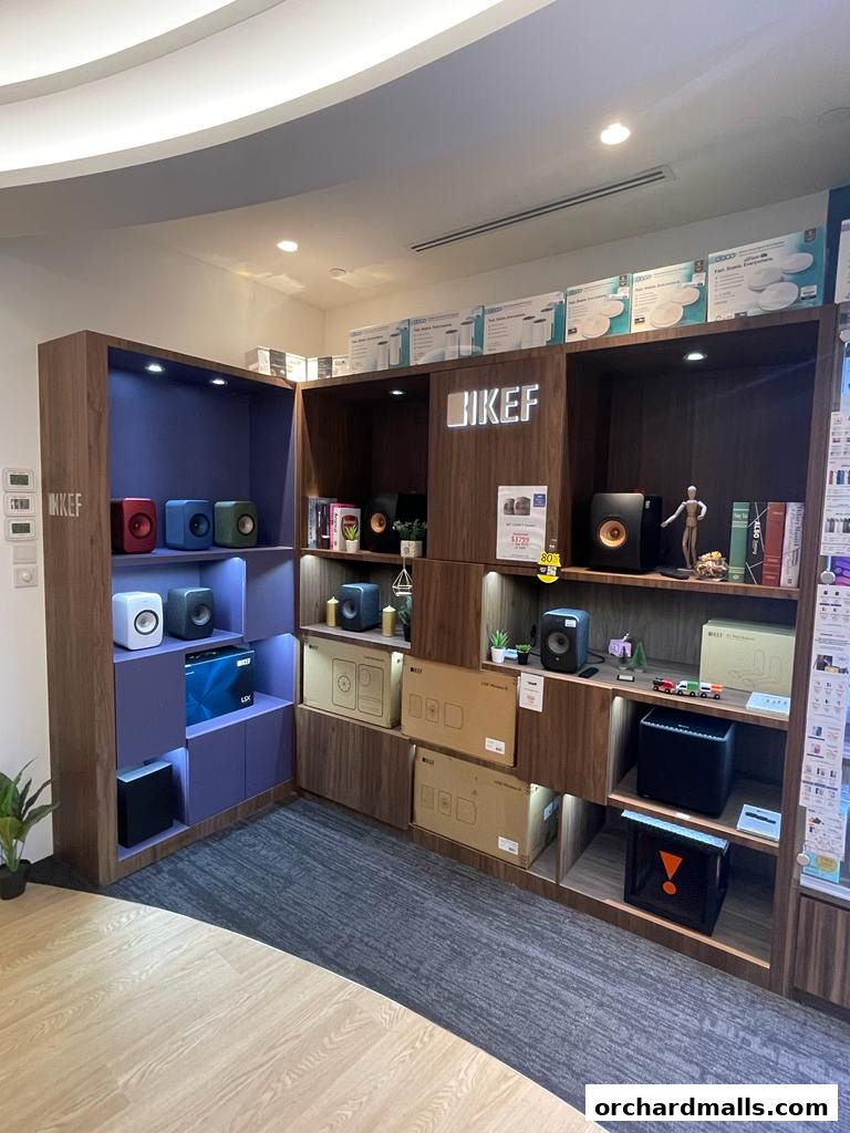 A retail display showcasing KEF audio equipment, including speakers and subwoofers, on wooden shelves.