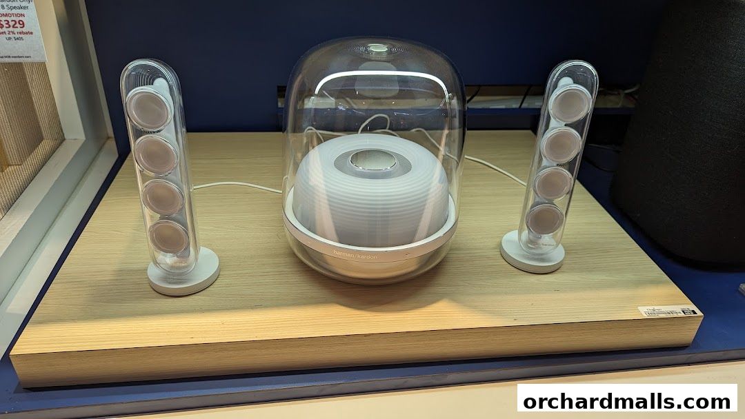 A Harman Kardon Onyx Studio 8 speaker system with two satellite speakers on display.