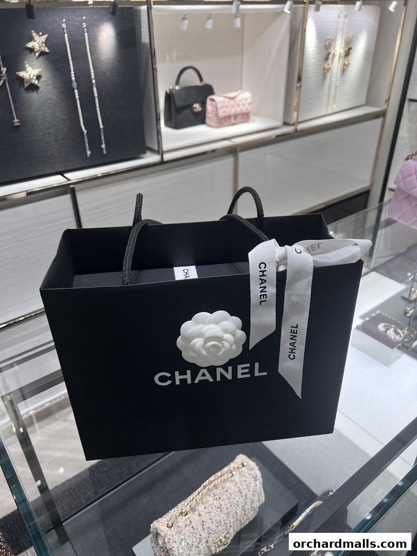 A Chanel shopping bag with a camellia flower and ribbon, showcasing luxury accessories.