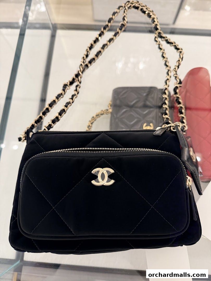 A close-up shot of a black Chanel handbag with a quilted design and gold chain strap.
