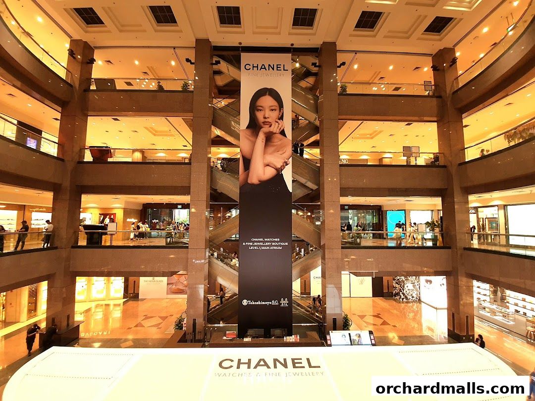 A large Chanel advertisement banner hangs in a multi-level shopping mall atrium.