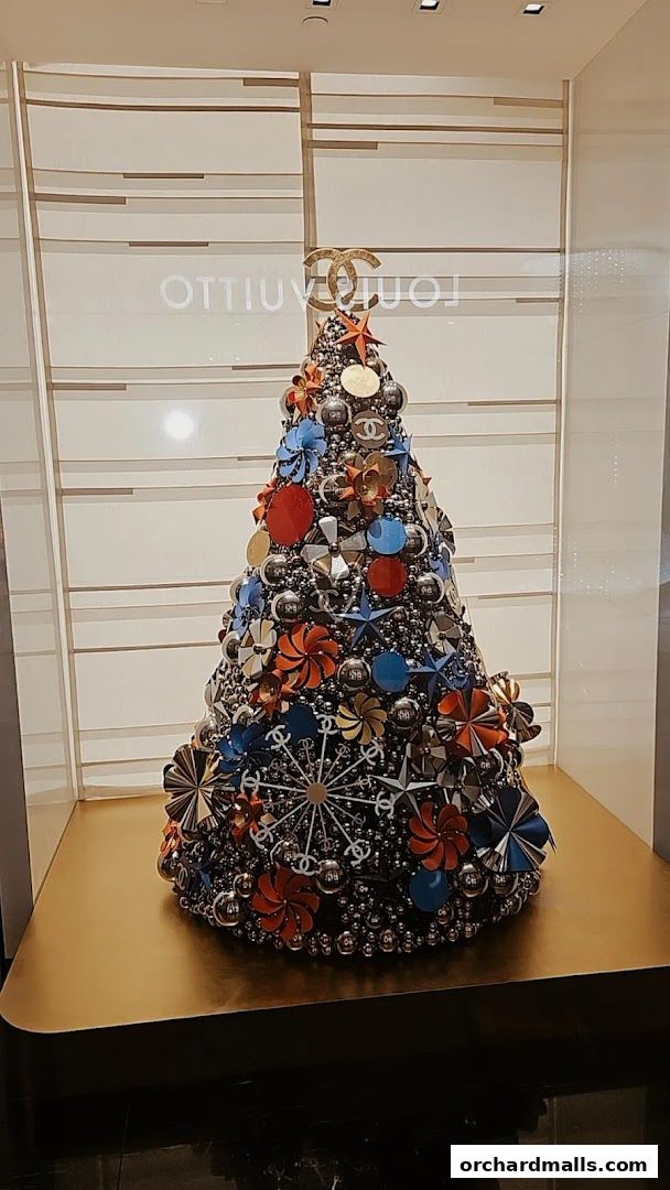 A festive Chanel-themed Christmas tree decorated with brand logos and ornaments.