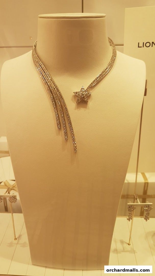 A diamond necklace and earrings displayed on a mannequin in a jewelry store.