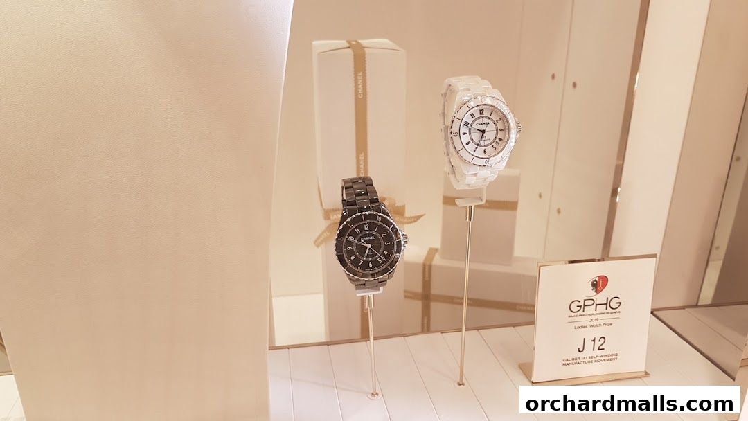 Chanel J12 watches displayed in a store window, one black and one white.