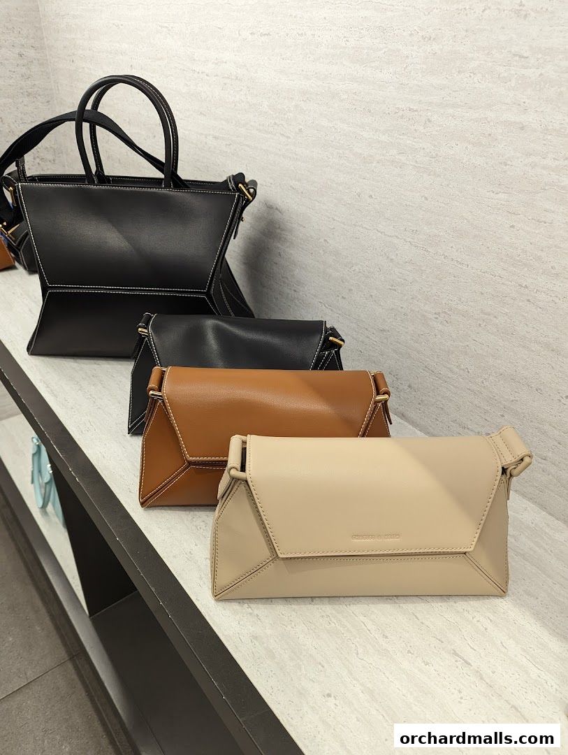 A display of stylish handbags in various colors on a shelf.