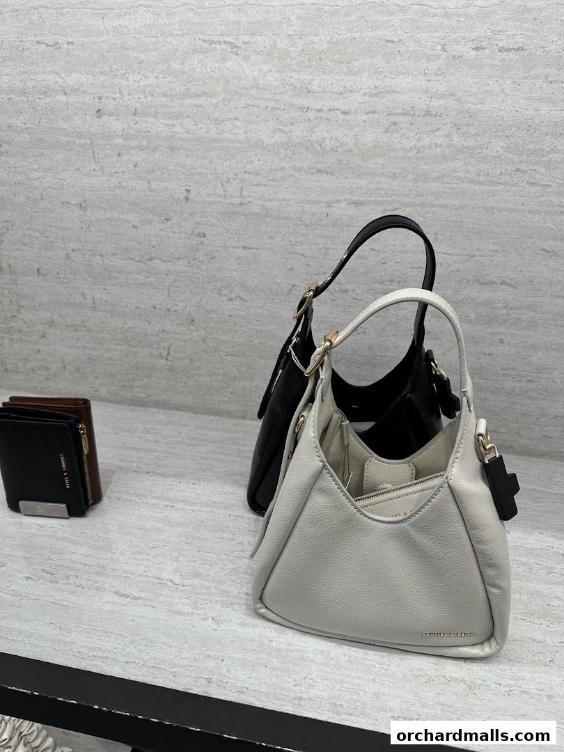 Two stylish handbags and wallets displayed on a marble countertop at Charles & Keith.