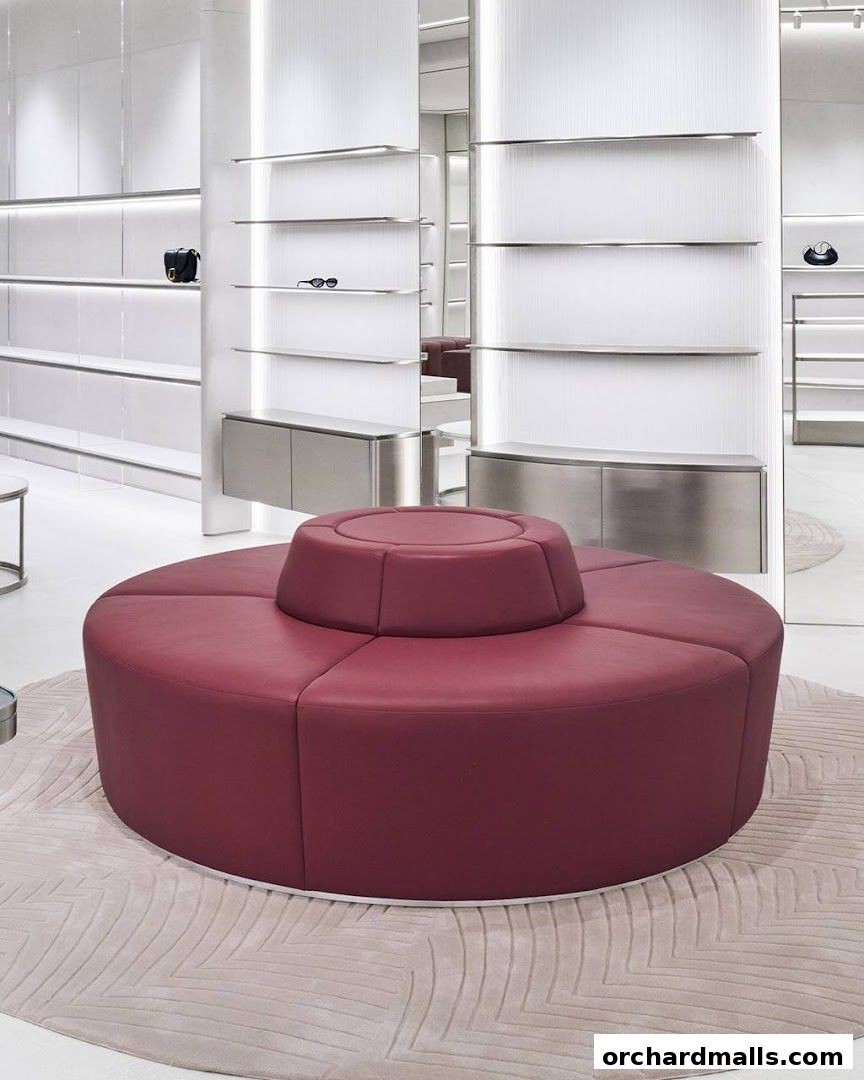 Interior of a modern retail store with shelves displaying handbags and sunglasses, and a circular red seating area.