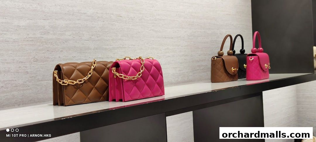 A display of stylish quilted handbags in various colors on a shelf.