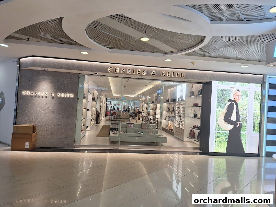 The Charles & Keith store at ION Orchard features a modern facade with illuminated signage and a large display window showcasing a model.