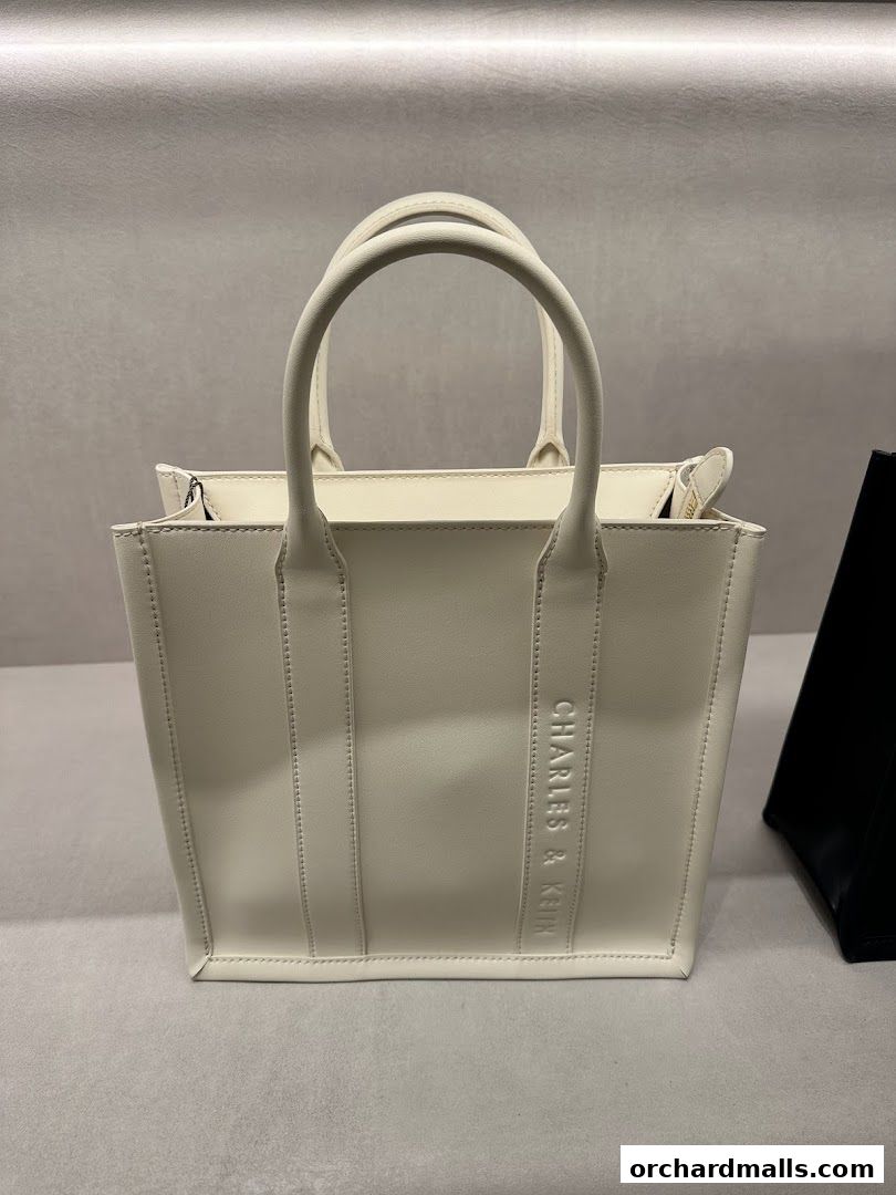 A stylish white tote bag with the Charles & Keith logo embossed on the side.
