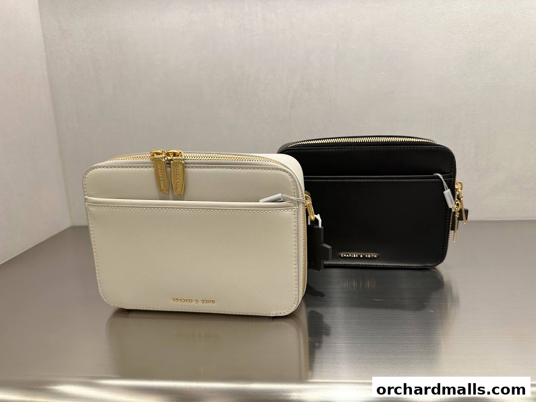 Two Charles & Keith handbags, one cream and one black, displayed on a reflective surface.