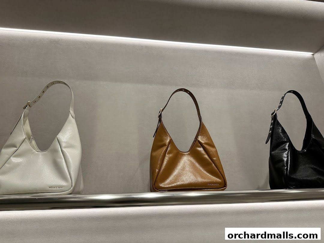 Three stylish handbags displayed on a shelf in a retail store.