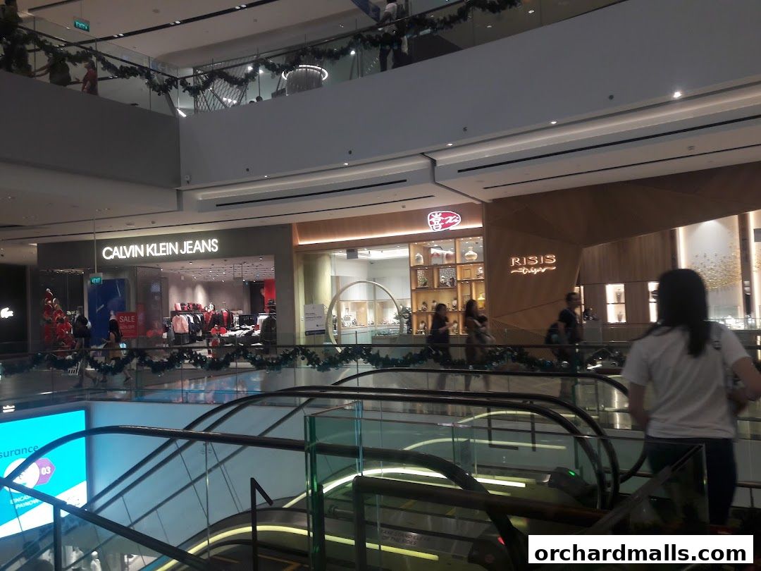 Interior view of a shopping mall with various retail stores and escalators.