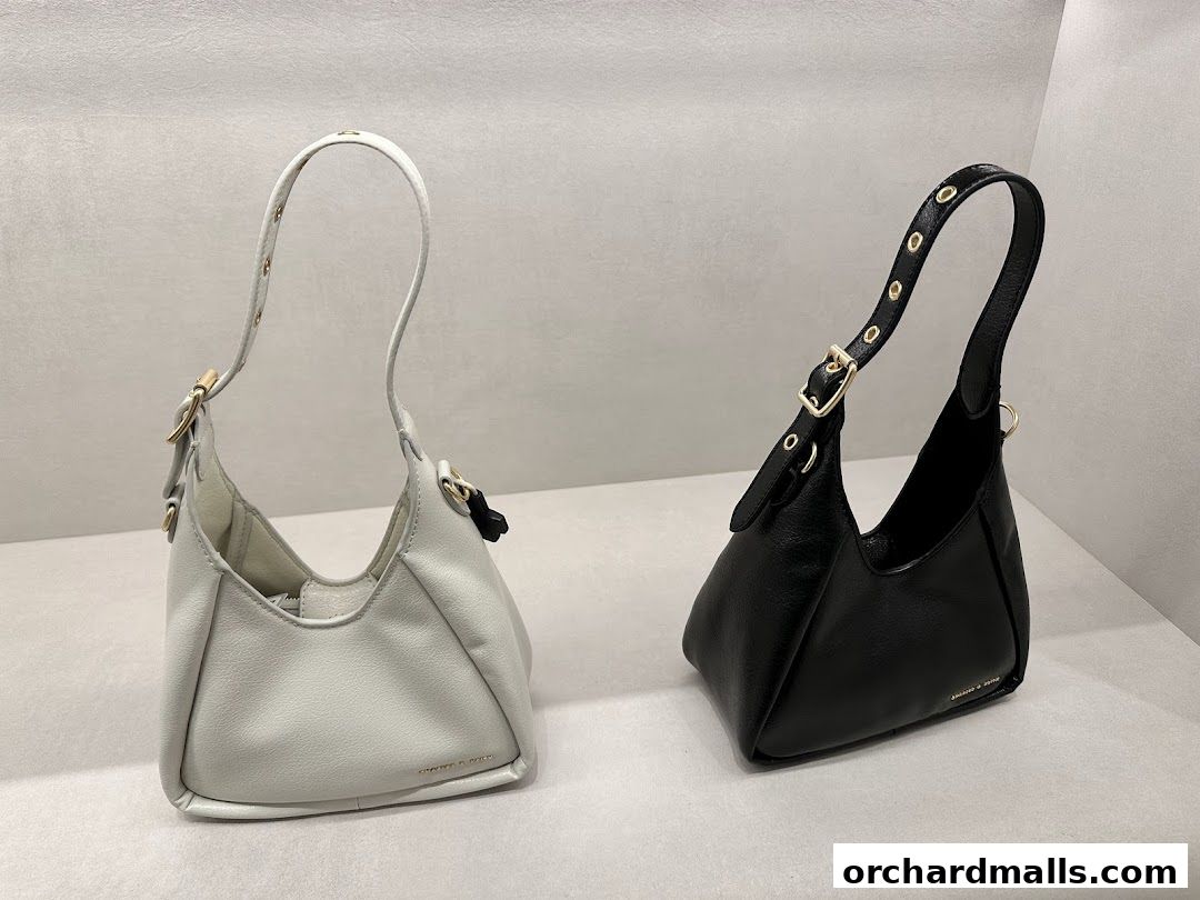 Two stylish handbags, one white and one black, displayed on a shelf.