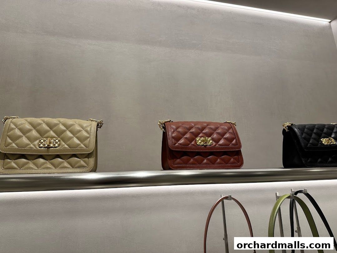 Quilted handbags in beige, brown, and black displayed on a shelf.