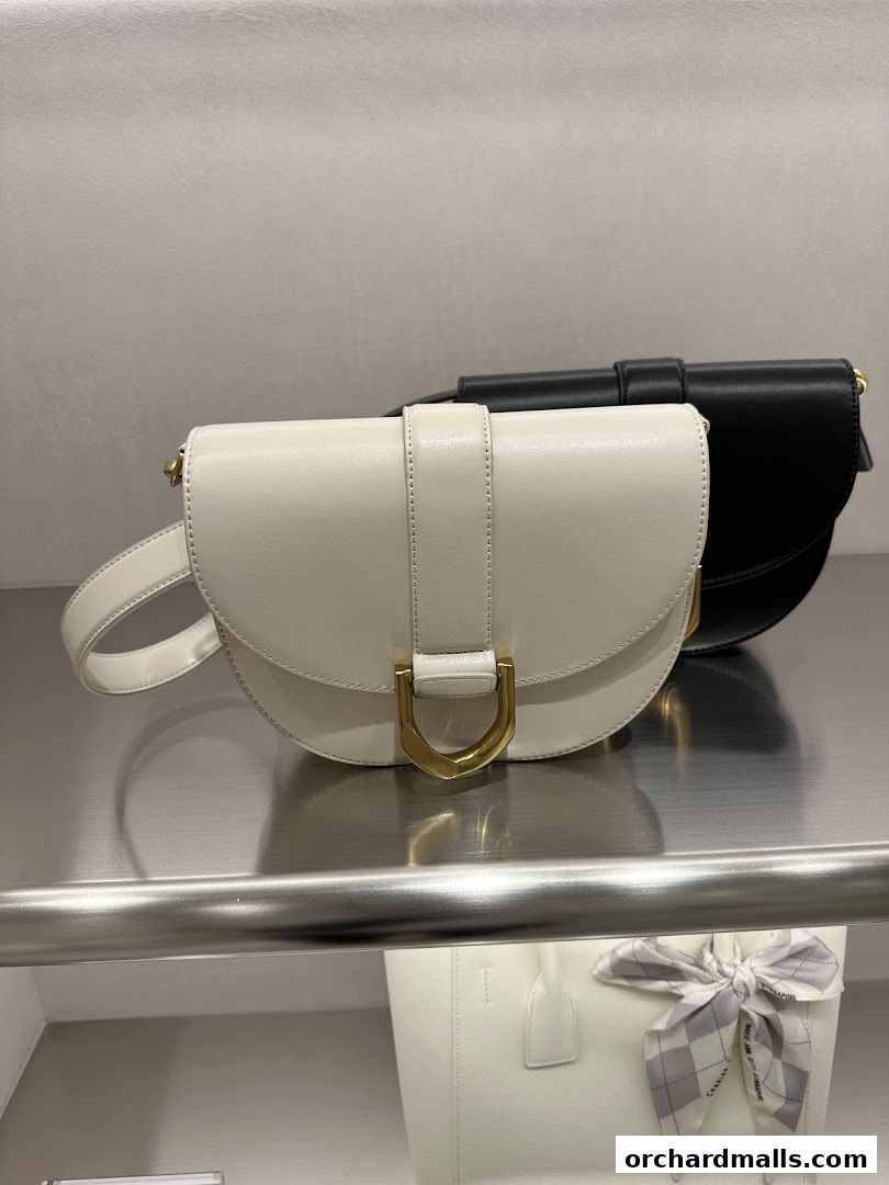 Elegant white and black handbags displayed on a shelf in a retail store.