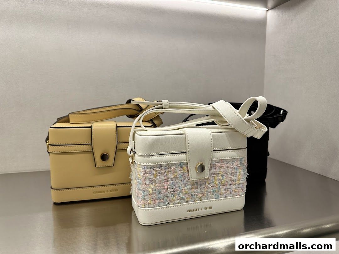 Stylish handbags from Charles & Keith displayed on a metallic shelf.