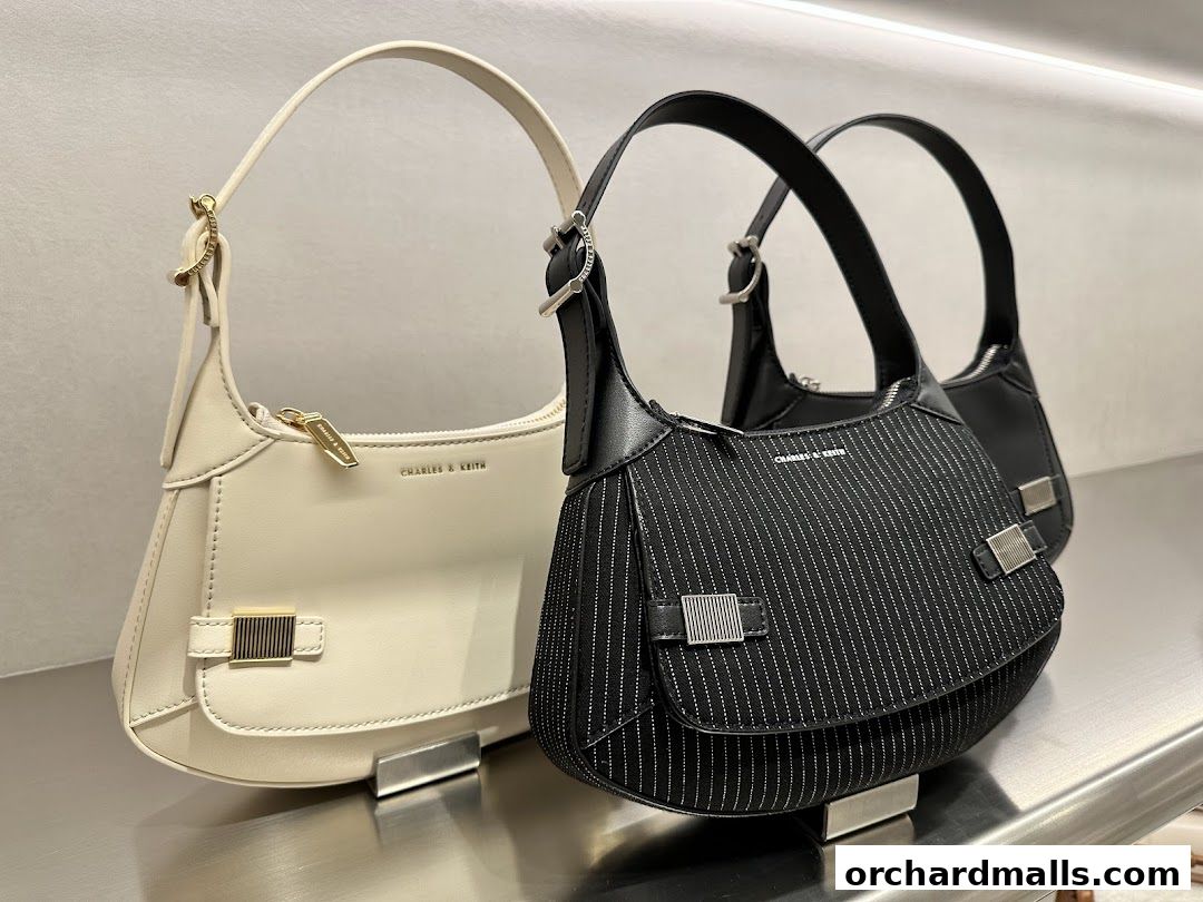 Stylish cream and black shoulder bags from Charles & Keith displayed on a shelf.