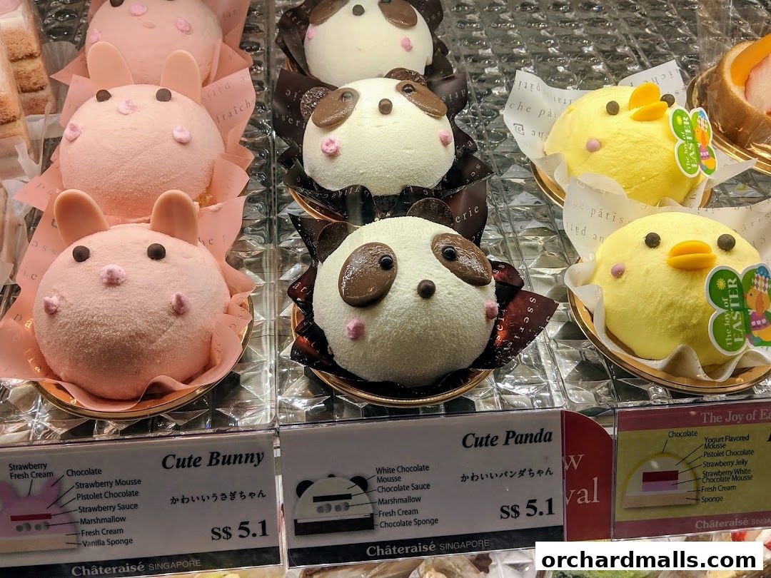 A display of cute animal-shaped cakes, including bunnies, pandas, and chicks.